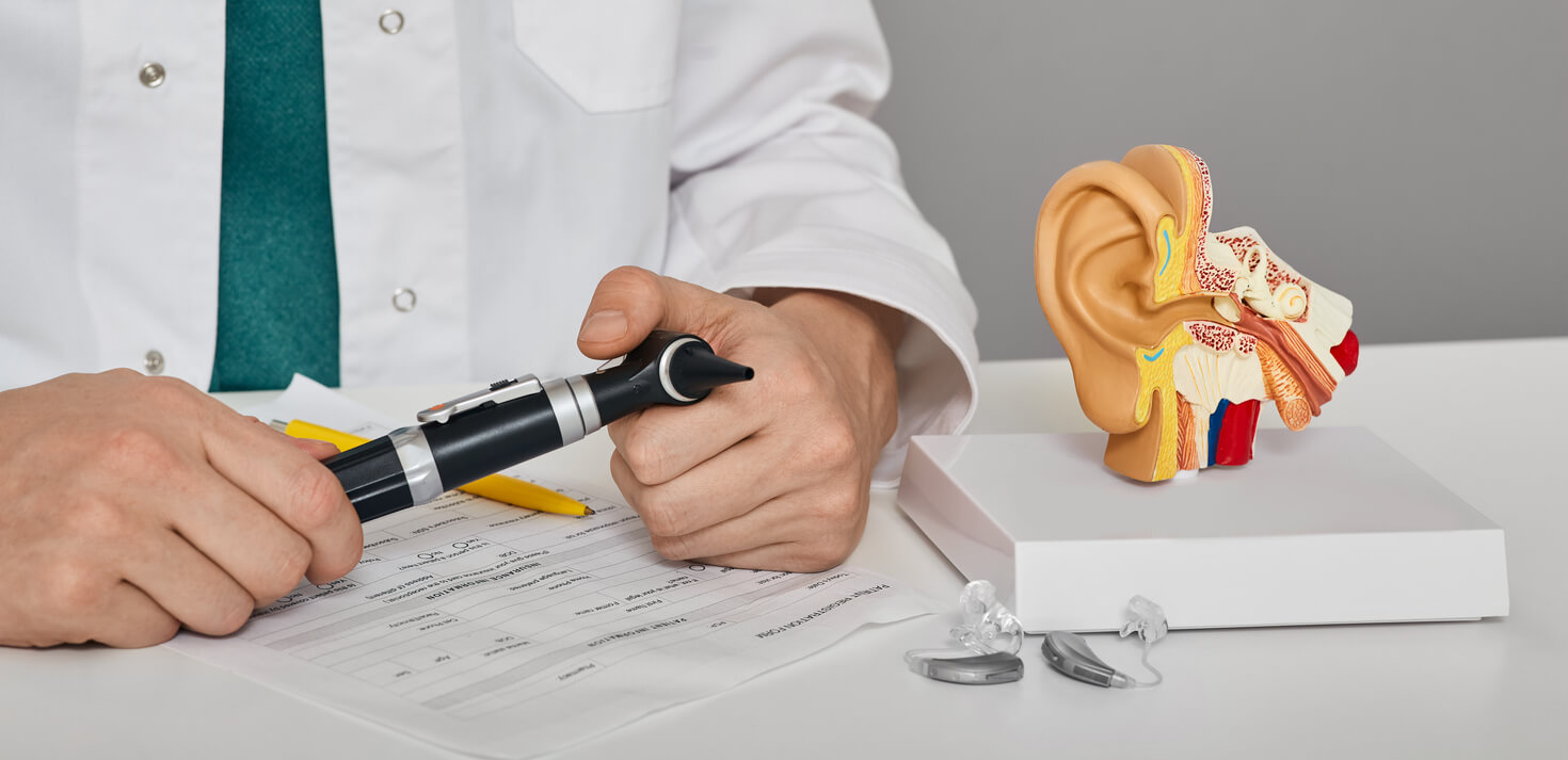 ENT doctor with otoscope in hands sitting in his audiology office.